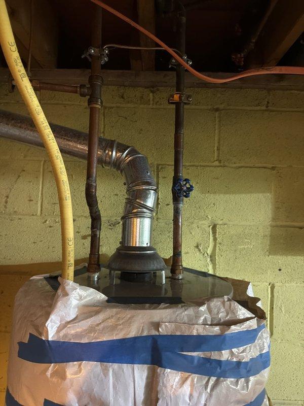 Responded to no hot water call at residential property. Upon arrival, inspected tanked water heater unit located in basement utility area. Assessed pilot light assembly and burner controls as reported by customer. Water heater appeared to be standard gas-fired unit with copper supply lines, pressure relief valve, and gas line connection. Unit showed existing insulation wrap with securing straps. Performed diagnostic evaluation of heating system components including gas valve, thermocouple, and pilot assembly. Verified proper gas supply via flexible gas line connection. Inspected all plumbing connections at top of unit including hot water outlet and cold water inlet with shut-off valve. Examined floor-mounted control components and verified proper installation of all safety devices. Restored hot water service to residence.