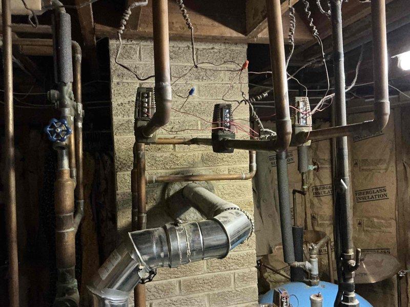 Performed estimate for 47-year-old boiler system experiencing no heat and no hot water production. Unit is a standard boiler, not a combination system. Assessed existing mechanical room infrastructure including aged copper piping, electrical panels, and venting configuration. Documented current system condition with photos showing metallic flue pipe installation, exposed utility connections, and overall mechanical room layout. Provided quote for new boiler replacement with updated venting system to restore heating and domestic hot water functionality.