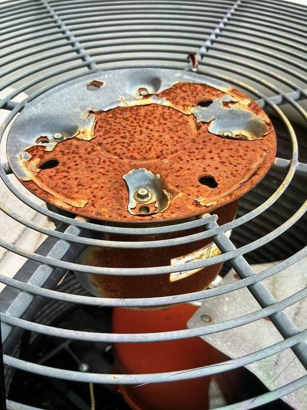 Completed routine cooling maintenance on 15-year-old air conditioning system. Inspected blower wheel assembly and noted significant dust accumulation on fan blades requiring cleaning attention. Observed extensive rust and corrosion on circular metal component within fan guard assembly, indicating advanced deterioration that may require future replacement to prevent system failure.