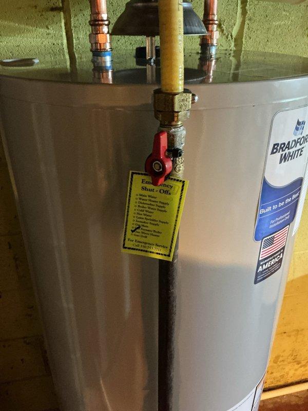 Installed a new 40-gallon Bradford White residential water heater in basement utility area. Installation included connecting copper hot and cold water supply lines with proper fittings, installing ball valve for water shut-off control, mounting white expansion tank to wall, and connecting yellow flexible gas line with emergency shut-off valve. All connections were properly soldered and secured, with pressure relief valve and discharge piping installed per code requirements.