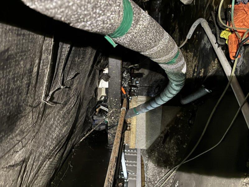 Replaced heat tape underneath mobile home trailer along approximately 45 feet of waterline routing from ground level up through support structure to rear of unit. Installed 50-foot heat tape section to ensure complete pipe coverage with adequate overlap at connection points. Two-person crew completed installation over 4-hour period due to elevated pipe configuration requiring coordinated positioning and securing of heat tape along vertical and horizontal runs through structural supports.