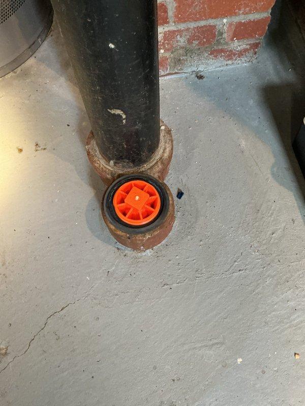 Responded to callback for main drain backup that remained unresolved from previous service visit. Upon arrival, inspected PVC P-trap assembly and floor drain system in basement utility area. Documented existing conditions showing drainage infrastructure with visible staining on concrete floor surrounding drain opening and corrosion present at pipe penetrations. Main drain line continues to experience backup issues requiring further investigation and corrective action to restore proper drainage function.