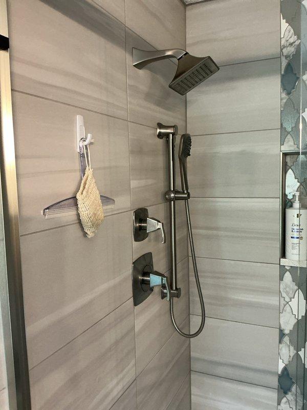 Responded to service call for broken shower handle in modern bathroom with oil-rubbed bronze fixtures. Upon inspection, found damaged shower valve cartridge with exposed mounting hardware and deteriorated wall material around the fixture opening. Removed defective cartridge assembly, identified manufacturer specifications from unit markings, and prepared area for replacement installation with proper sealing to prevent water intrusion behind wall surface.