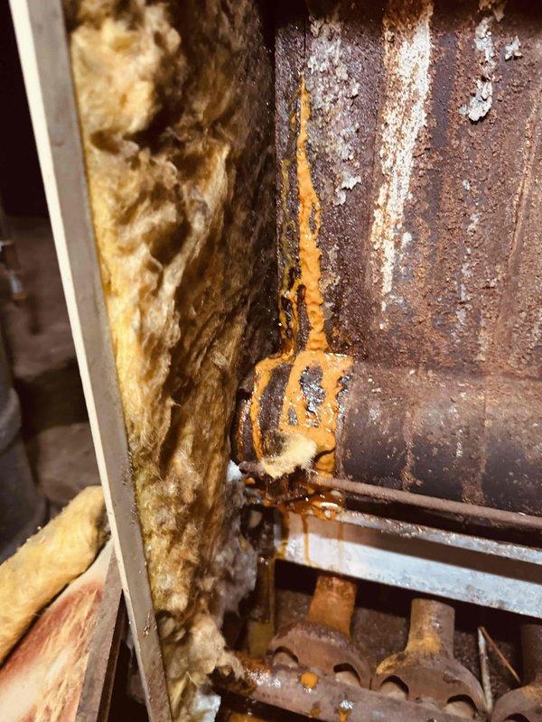 # HVAC Service - Boiler

Performed comprehensive inspection and assessment of 21-year-old boiler system experiencing operational issues prior to heating season. Upon examination, discovered significant internal corrosion on heat exchanger surfaces with rust deposits, white mineral accumulation, and unusual orange-yellow discharge indicating potential combustion byproduct contamination or moisture intrusion. Identified corroded pipe union connections with active rust staining and evidence of water seepage at threaded joints. Documented deteriorated fiberglass insulation and overall component degradation consistent with age and environmental exposure. Advised customer of findings regarding heat exchanger integrity concerns and piping system corrosion that may require further remediation to ensure safe and reliable operation throughout the heating season.