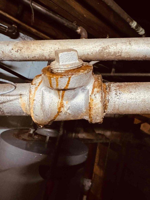 # HVAC Service - Boiler

Performed comprehensive inspection and assessment of 21-year-old boiler system experiencing operational issues prior to heating season. Upon examination, discovered significant internal corrosion on heat exchanger surfaces with rust deposits, white mineral accumulation, and unusual orange-yellow discharge indicating potential combustion byproduct contamination or moisture intrusion. Identified corroded pipe union connections with active rust staining and evidence of water seepage at threaded joints. Documented deteriorated fiberglass insulation and overall component degradation consistent with age and environmental exposure. Advised customer of findings regarding heat exchanger integrity concerns and piping system corrosion that may require further remediation to ensure safe and reliable operation throughout the heating season.