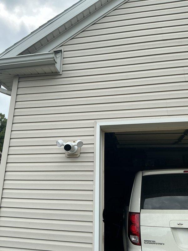 Installed exterior security camera fixture on residential siding with proper mounting and electrical connections. Relocated garage ceiling light to center position for improved illumination coverage, including circuit verification at main electrical panel.