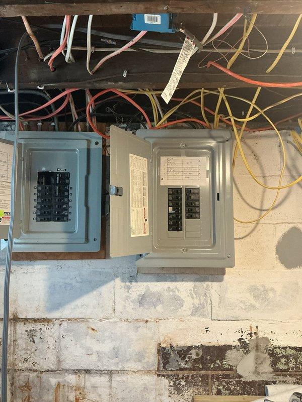 Completed electrical panel replacement at residential property in preparation for fall season. Installed new circuit breaker panels to replace outdated equipment, ensuring proper load distribution and code compliance. Exterior meter base and junction box connections verified and secured with appropriate conduit routing along building siding. Interior basement installation included mounting dual panel configuration on concrete block wall with organized circuit breaker arrangement. All electrical connections tested and confirmed operational, improving overall system safety and reliability for the residence.