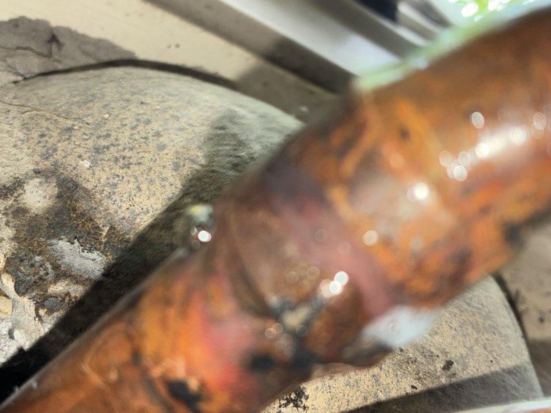 Located and identified a slow refrigerant leak in the lineset showing visible corrosion and deterioration at the pipe connection point. Added 5 pounds of refrigerant to restore system cooling capacity as a temporary measure to maintain comfort until permanent repair can be completed. Documented leak location with photographs showing extensive oxidation and surface degradation on copper piping. Scheduled follow-up appointment for lineset repair with additional technician assistance.