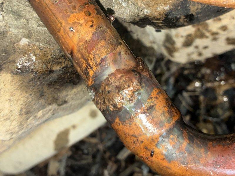 Located and identified a slow refrigerant leak in the lineset showing visible corrosion and deterioration at the pipe connection point. Added 5 pounds of refrigerant to restore system cooling capacity as a temporary measure to maintain comfort until permanent repair can be completed. Documented leak location with photographs showing extensive oxidation and surface degradation on copper piping. Scheduled follow-up appointment for lineset repair with additional technician assistance.