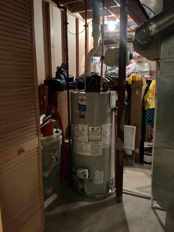 Replaced existing Rheem power vent water heater with new Bradford White tank unit in basement utility area. Installation included new ball valve and thermal expansion tank to meet current plumbing code requirements. Connected new exhaust system to existing ABS vent line routing above finished basement ceiling. All copper and black pipe connections completed with proper fittings and valves. Unit installed between wall studs with fire extinguisher mounted nearby for safety compliance. System tested and verified operational with 10-year manufacturer warranty coverage.