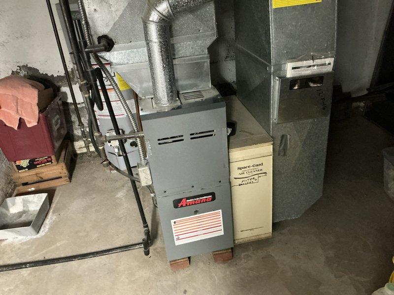 Conducted comprehensive assessment of existing residential HVAC system for replacement estimate. Evaluated indoor Amana furnace unit and associated ductwork in basement utility area, documenting equipment age, condition, and configuration. Inspected outdoor air conditioning condenser unit, electrical disconnect, and installation pad. Photographed both indoor and outdoor components to provide detailed documentation for replacement system specifications and scope of work.