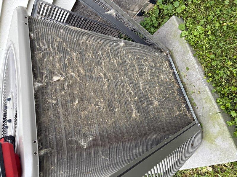 # HVAC Maintenance - Cooling

Completed routine MVP cooling maintenance visit on a 6-year-old residential air conditioning system. Upon arrival, performed comprehensive inspection of outdoor condenser unit, which revealed heavy accumulation of dirt, dust, and debris throughout the condenser coil fins and filter surfaces. The buildup showed significant grayish-tan coating with streaked patterns indicating extended period between services, along with darker discoloration and clumping between fin spaces.

Conducted thorough cleaning of condenser coil fins to remove accumulated debris and restore proper airflow through the unit. Cleaned filter surfaces that displayed considerable particulate matter accumulation affecting system efficiency. Verified condenser fan operation and inspected cylindrical fan housing with ventilation grilles for proper function. Performed diagnostic measurements using electronic testing equipment to assess system performance parameters.

Inspected unit cabinet and