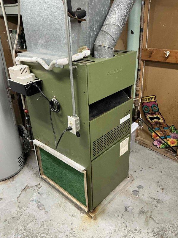 Responded to emergency service call for burning plastic odor originating from furnace area that required fire department intervention. Inspected 1984 Rheem furnace and matching air conditioning system, both units operating beyond their expected service life. Documented existing equipment condition including aging furnace with visible wear, deteriorated components, and outdoor condensing unit showing significant weathering and accumulated debris. Provided comprehensive replacement estimate for new heating and cooling system to address safety concerns and equipment failure risk.