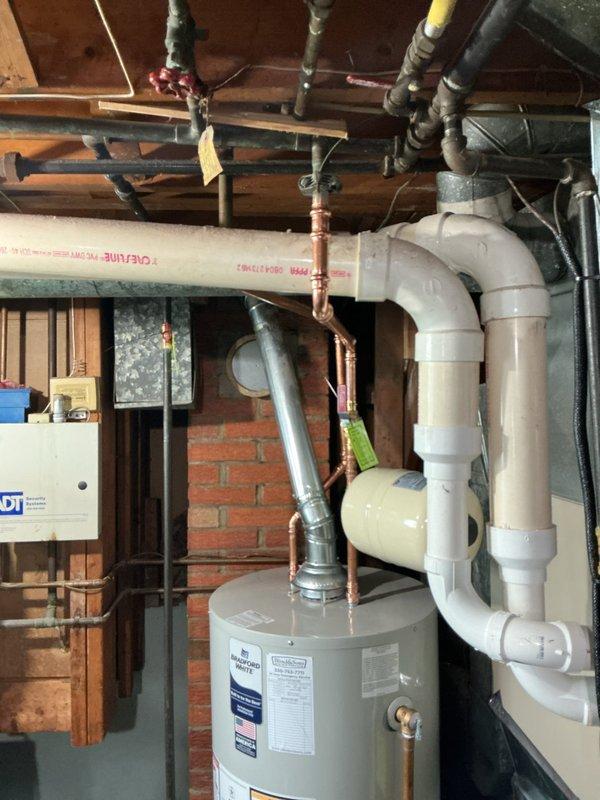 Installed new 40-gallon Bradford White short water heater (model RG240S6N) with 6-year manufacturer warranty, elevated on bricks above basement floor. Installation included new ball valve, expansion tank, and gas shut-off valve. Replaced old gate valve on main water line with new ball valve, rebuilding piping back to meter with water department shutting off supply at street. Snaked main drain line approximately 75 feet from cleanout at base of stack to road connection. Removed existing brass cap and installed new 2.5-inch T-cone plug at cleanout access point.