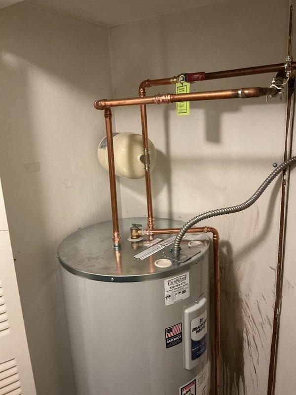 Replaced existing 50-gallon electric water heater with new Bradford White unit and brought installation up to current code compliance. Installation included positioning unit in water pan with drain line routed to floor drain, installing thermal expansion tank, and completing proper electrical bonding of the system. Removed and hauled away old water heater and water softener unit from premises.