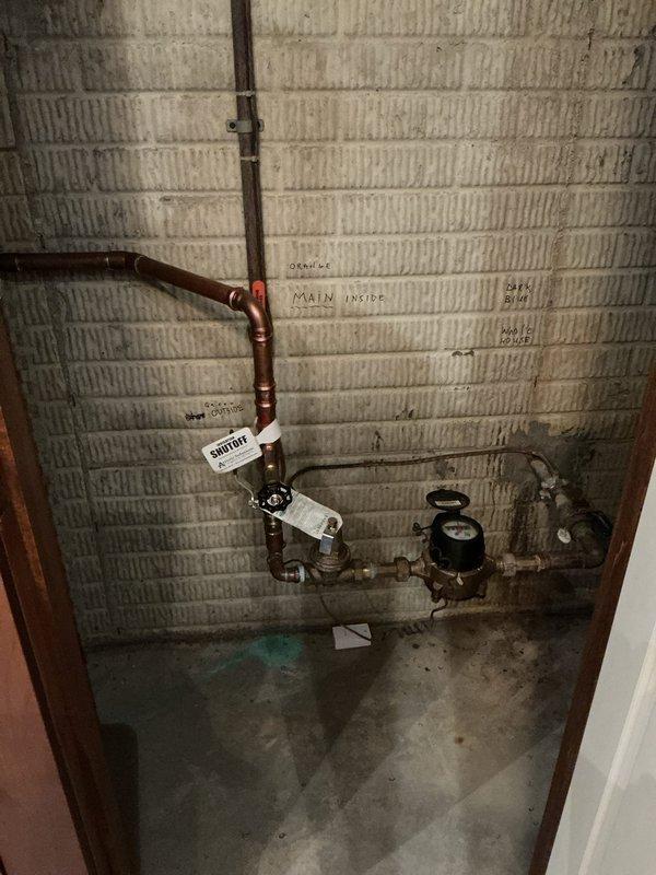 Responded to service call for estimate on automatic shut-off valve installation in basement. Conducted site assessment of existing plumbing system, which includes copper supply lines with main shutoff valve configuration along painted brick wall. Photographed current plumbing layout showing main water supply lines, existing manual shutoff valves, pressure gauge, and branching distribution lines to document installation location and existing conditions for estimate preparation.