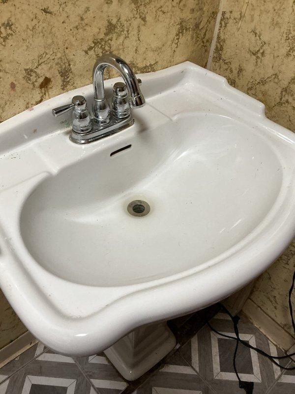 Responded to a slow-draining bathroom pedestal sink. Upon inspection, accessed the drain assembly from below through the basement ceiling area where the waste line and shut-off valve were visible. Cleared the obstruction in the drain line, restoring proper drainage flow to the fixture. Tested the sink to confirm the issue was resolved and proper drainage was restored.