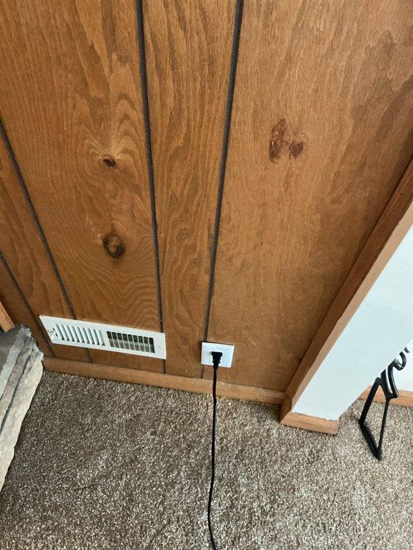 Installed spark guard protection device on existing 2-wire electrical system where GFCI installation was not feasible. Trimmed wood paneling to access junction box and secured device with 3-inch screws to properly reach the recessed electrical box. Completed low-voltage cable outlet installation and organized wiring routing along wall and carpet transition.