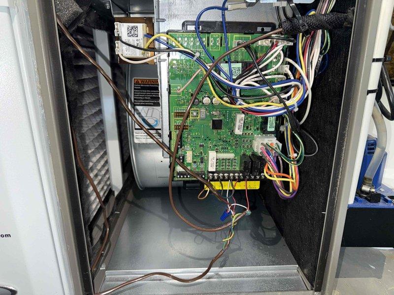 Completed BS-MVP recurring cooling maintenance visit on HVAC system. Performed comprehensive inspection of unit interior, including electronic control board, wiring connections, capacitor, and refrigeration components. Documented system condition with interior access panel removed, revealing complex PCB with multiple wire connections and terminal blocks. Observed dust accumulation on interior surfaces and minor corrosion on terminal connections, typical of normal system operation. All electrical connections verified secure, and control board components functioning within normal parameters.