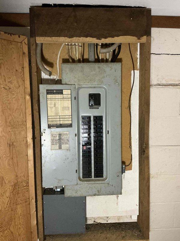 Conducted on-site assessment for whole home backup generator installation. Evaluated existing electrical infrastructure, including main service panel configuration and capacity. Documented current General Electric load center with dual columns of circuit breakers and main breaker disconnect. Assessed panel condition, age, and available capacity for generator integration. Photographed electrical panel interior, circuit breaker arrangement, and service entrance wiring to determine compatibility requirements for automatic transfer switch installation. Evaluated installation location accessibility, wall construction, and structural considerations for generator placement. Reviewed existing electrical system to calculate total home load requirements and determine appropriate generator sizing specifications for complete backup power coverage.