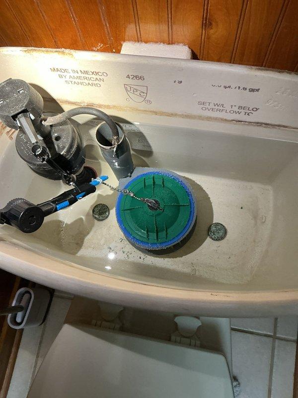 Responded to complaint of toilet continuously running water every 5-10 minutes after flushing in 1991-built residence. Upon inspection, removed tank lid from American Standard model 4266 toilet and identified faulty flapper valve assembly causing intermittent refill cycles. The existing green and blue circular flapper showed signs of deterioration and was not sealing properly against the flush valve seat, allowing water to slowly leak from tank to bowl and triggering the fill valve to activate repeatedly. Replaced worn flapper with new compatible unit, adjusted chain length for proper closure, and tested flush mechanism multiple times to verify complete seal and proper water level maintenance. Confirmed fill valve and overflow tube were functioning correctly with no additional adjustments needed. System now operates normally with no phantom flushing between use cycles.