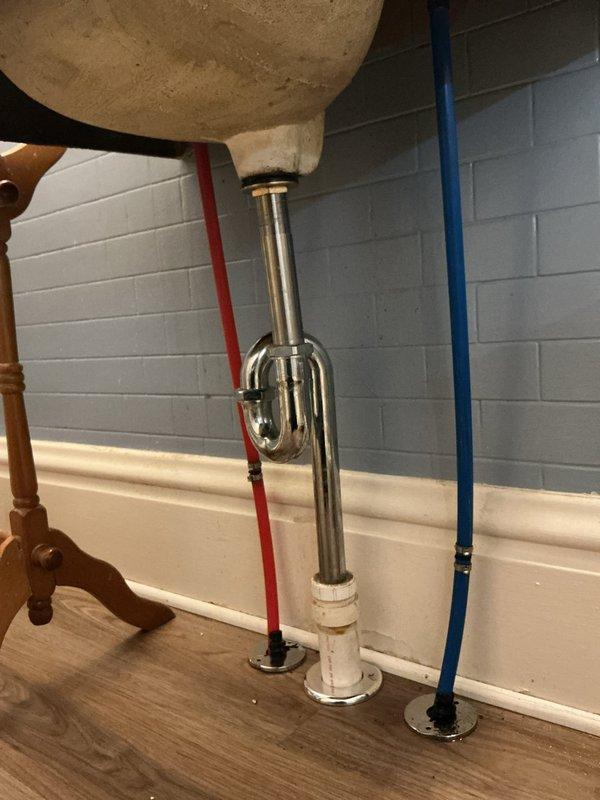 Responded to active water leak from faulty right valve knob in century-old residential property. Inspected water heater connections and bathroom sink plumbing assembly, identifying compromised valve mechanism causing continuous water discharge. Replaced defective valve hardware with chrome-plated fixtures, ensuring proper seal and function. Verified hot and cold water supply lines (PEX tubing with standard red/blue coding) maintained proper pressure and showed no signs of deterioration. Tested P-trap assembly and drain connections for leaks, confirmed all plumbing components operational with no active water flow issues upon completion.