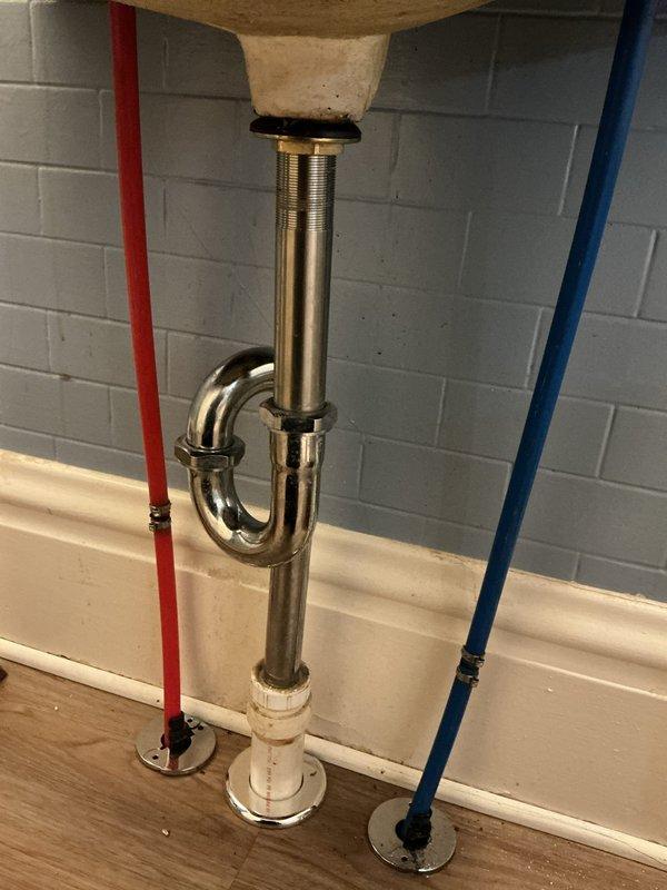 Responded to active water leak from faulty right valve knob in century-old residential property. Inspected water heater connections and bathroom sink plumbing assembly, identifying compromised valve mechanism causing continuous water discharge. Replaced defective valve hardware with chrome-plated fixtures, ensuring proper seal and function. Verified hot and cold water supply lines (PEX tubing with standard red/blue coding) maintained proper pressure and showed no signs of deterioration. Tested P-trap assembly and drain connections for leaks, confirmed all plumbing components operational with no active water flow issues upon completion.
