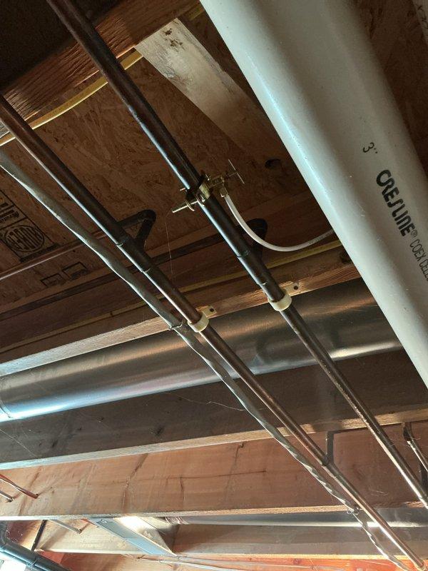 Responded to water leak from copper refrigerator supply line in basement. Upon inspection, located the compromised copper water line running through the exposed ceiling joists. Assessed the existing plumbing configuration, including multiple copper pipe runs secured with mounting brackets throughout the unfinished ceiling space. Identified the source of the leak and performed necessary repairs to restore proper water flow to the refrigerator while eliminating the active leak. Documented the existing plumbing infrastructure and repair work with photographs for service records.