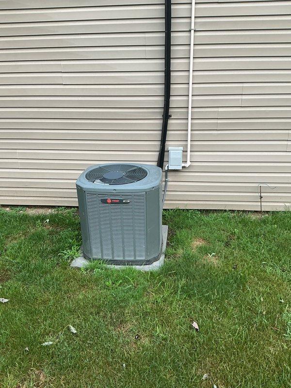 Completed full HVAC system installation including 80% downflow furnace with metal supply ductwork, air conditioning condenser unit, and hot water heater. The Trane AC condenser was positioned on a concrete pad with proper lineset routing and electrical disconnect mounted to exterior siding. Interior mechanical room installation included the downflow furnace with galvanized ductwork transition and new water heater with copper supply connections, all installed per manufacturer specifications and local code requirements.