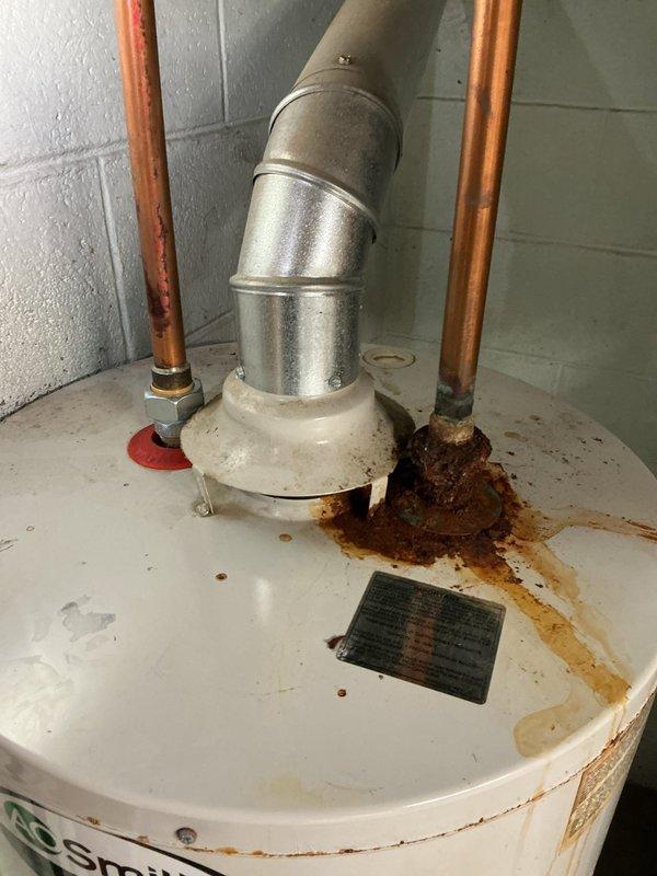 Conducted assessment of existing A.O. Smith tanked water heater for replacement quote. Unit exhibited significant rust and corrosion on top surface and at copper pipe connection points, indicating moisture exposure and aging infrastructure. Evaluated installation configuration including copper supply lines, pressure relief valve, and metal vent pipe connection to overhead ductwork. Documented current water heater condition in basement utility room, noting all plumbing connections, HVAC ductwork proximity, and PVC drainage systems. Provided comprehensive replacement quote based on observed deterioration and standard installation requirements.