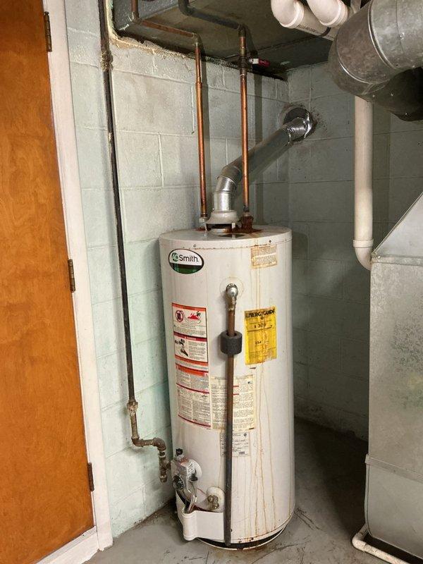 Conducted assessment of existing A.O. Smith tanked water heater for replacement quote. Unit exhibited significant rust and corrosion on top surface and at copper pipe connection points, indicating moisture exposure and aging infrastructure. Evaluated installation configuration including copper supply lines, pressure relief valve, and metal vent pipe connection to overhead ductwork. Documented current water heater condition in basement utility room, noting all plumbing connections, HVAC ductwork proximity, and PVC drainage systems. Provided comprehensive replacement quote based on observed deterioration and standard installation requirements.