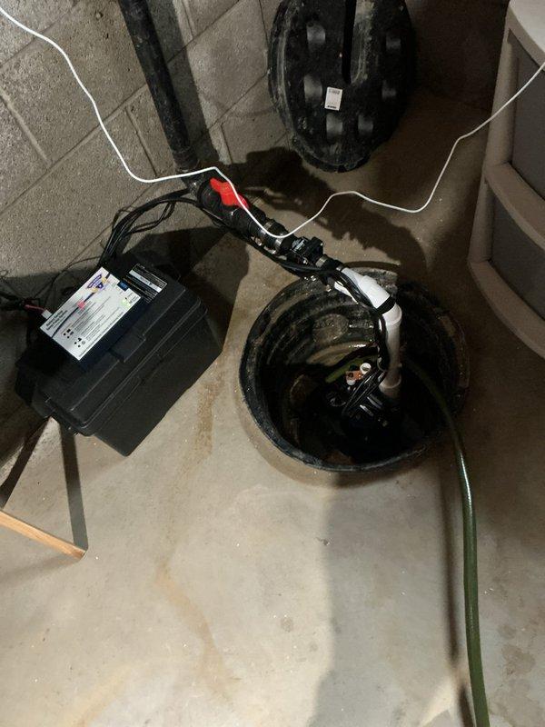 Removed existing battery backup system from sump pump installation and replaced with new battery backup unit, including fresh battery and associated piping and fittings. Work involved disconnecting old power cables and alligator clip connections, installing new backup system adjacent to existing sump pump basin, and ensuring proper electrical connections between battery unit and pump mechanism. All necessary pipe modifications and fittings were completed to integrate the new backup system with the existing sump pump configuration for reliable emergency operation during power outages.