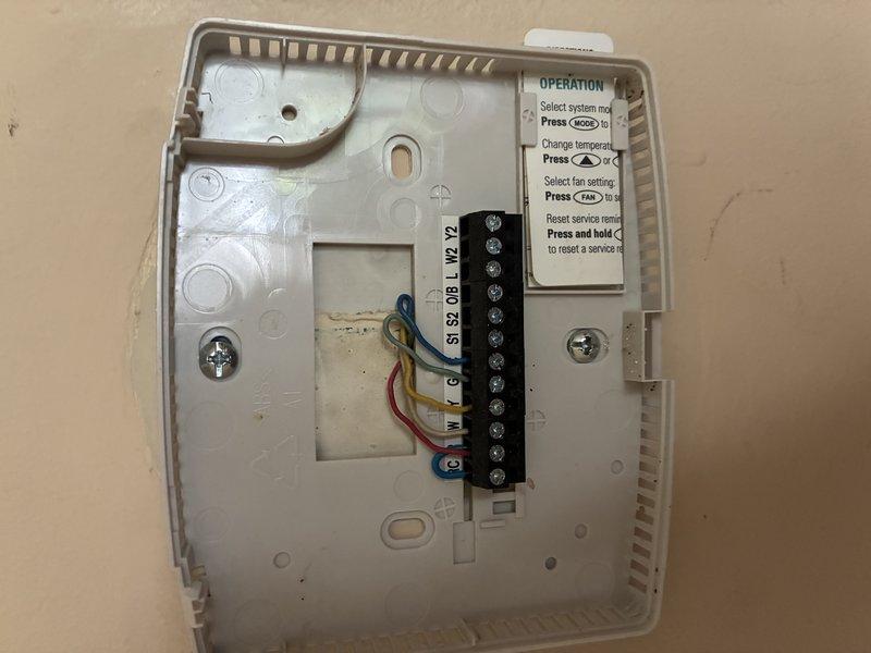 Responded to service call for malfunctioning thermostat. Inspected AprilAire programmable thermostat, removed cover to examine internal wiring and terminal connections. Verified all wire connections at terminal strip were secure, checked system operation, and confirmed thermostat was functioning properly with display reading accurately at 79°F.