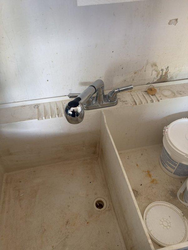 Responded to service call for utility sink faucet evaluation. Upon arrival, inspected double-basin laundry sink with chrome two-handle faucet assembly. Customer referenced previous diagnosis from April regarding faucet issue, though no prior work order or estimate was documented in system. Performed visual assessment of faucet installation, mounting hardware, and surrounding plumbing fixtures. Documented current condition of sink area and faucet assembly with photographs for service records.