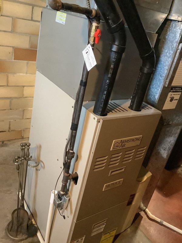 Conducted on-site evaluation for furnace replacement of existing 22-year-old gas heating system. Assessed current Armstrong Air furnace installation, associated ductwork, venting configuration, and auxiliary equipment including Aprilaire humidifier system. Documented existing equipment specifications, physical layout, and mechanical connections. Photographed current system setup showing furnace unit, electrical disconnect, gas piping assembly with shutoff valves, exhaust/intake venting, and surrounding utility space infrastructure. Provided comprehensive replacement estimate for new high-efficiency gas furnace installation with proper venting and all necessary connections to existing duct system.