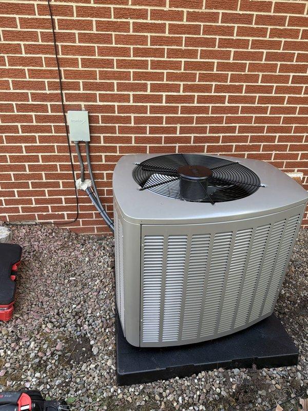 Completed installation of air conditioning system with evaporator coil as part of second-phase HVAC project. Installed outdoor condensing unit on rubber isolation pad with proper gravel base, mounted electrical disconnect box with FLNR 250 amp Littelfuse fuses, and ran refrigerant lines and electrical conduit along exterior brick wall. System tested and operational upon completion.