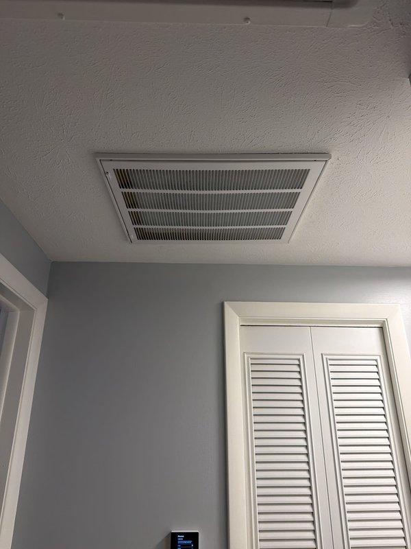 Completed full ductless mini-split system installation including attic-mounted air handler with new ductwork distribution and single indoor wall-mounted head unit. Installed gray metal air handler on platform between attic joists with proper structural support, ran flexible supply and return ductwork throughout attic space with appropriate insulation, and mounted interior ceiling register with white louver grille for conditioned air distribution. Installed indoor ductless head unit in living space with thermostat control panel for zone temperature management, ensuring proper refrigerant line connections, condensate drainage, and electrical service to both indoor and outdoor components for complete system operation.