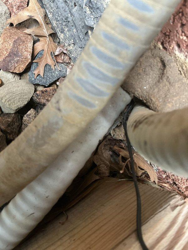 Responded to callback regarding humidifier issue originally addressed ten months prior. Upon arrival, conducted thorough inspection of humidifier system and associated components. During exterior unit examination, discovered severely deteriorated drain hose with complete outer layer disintegration and exposed internal reinforcement mesh. The flexible hose showed extensive weathering and material breakdown, compromising drainage function. Documented damage with photographs showing failed hose condition and positioning relative to outdoor condensing unit. Replaced damaged drain line with new corrugated drainage tubing to restore proper condensate removal. Verified proper drainage flow and system operation upon completion.