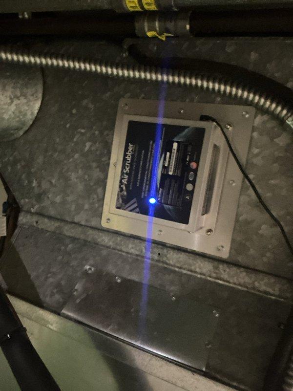 Completed MVP cooling maintenance visit on 9-year-old system. Inspected and photographed dual-run capacitor showing normal aging with secure wire connections across all terminals. Verified Air Scrubber plus air purification system operational with blue UV indicator light functioning properly within air handler compartment.