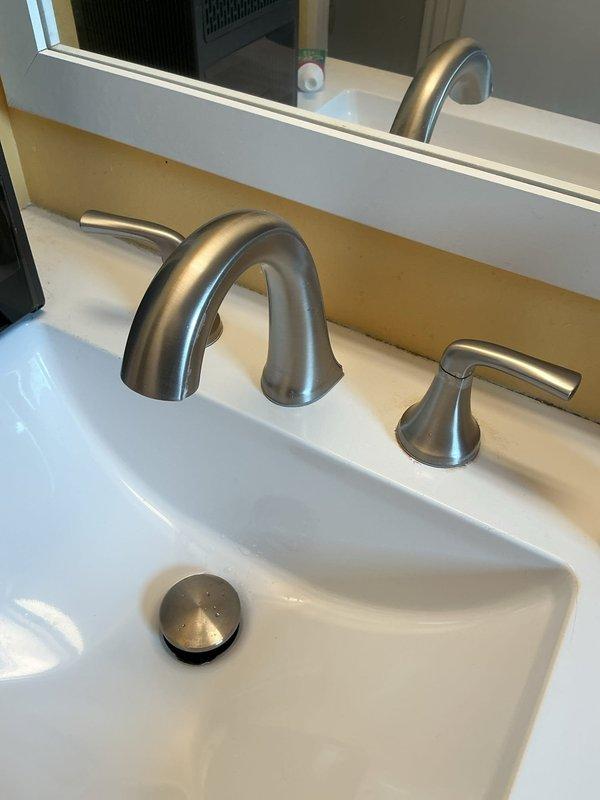 Responded to a leaking bathroom sink faucet equipped with a widespread three-piece fixture in brushed nickel finish. Diagnosed the issue as a failed valve cartridge in one of the handles, removed the defective cartridge, and installed a replacement component. Tested the faucet operation and verified no leaks were present upon completion.