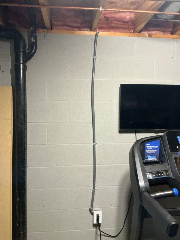 Responded to a GFCI tripping issue affecting a treadmill circuit in a basement workout area. The treadmill was previously installed on a shared GFCI-protected circuit with two other outlets. Upon investigation, determined that the treadmill's motor load was causing nuisance tripping of the GFCI device. Installed new dedicated circuit with surface-mounted EMT conduit and non-GFCI receptacle to isolate the treadmill from the existing GFCI-protected outlets, matching the configuration of the other two circuits in the space. Verified proper operation of all circuits and confirmed treadmill now functions without tripping issues.