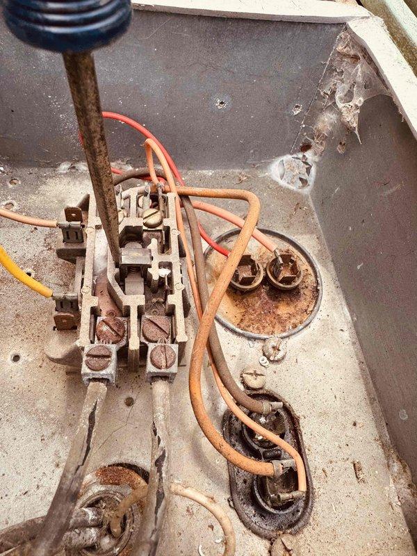# HVAC Service Call - Air Conditioning System Inspection and Assessment

Responded to service call for a 15-year-old air conditioning system failing to maintain desired temperature setpoint. Upon arrival, conducted comprehensive visual inspection of both indoor and outdoor components to diagnose cooling deficiency.

Exterior condenser unit examination revealed significant environmental deterioration affecting system integrity. Noted extensive rust staining on ventilation grille louvers with vertical corrosion patterns indicating prolonged moisture exposure. Surrounding wall surfaces exhibited water damage, discoloration, and biological growth patterns suggesting drainage or condensate management issues contributing to accelerated equipment degradation.

Interior electrical panel inspection uncovered critical maintenance concerns. Documented heavy corrosion and oxidation on multiple circular junction terminals and connection points throughout control assembly. Rust formation on metal mo