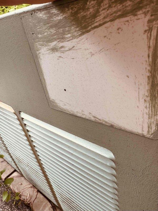 # HVAC Service Call - Air Conditioning System Inspection and Assessment

Responded to service call for a 15-year-old air conditioning system failing to maintain desired temperature setpoint. Upon arrival, conducted comprehensive visual inspection of both indoor and outdoor components to diagnose cooling deficiency.

Exterior condenser unit examination revealed significant environmental deterioration affecting system integrity. Noted extensive rust staining on ventilation grille louvers with vertical corrosion patterns indicating prolonged moisture exposure. Surrounding wall surfaces exhibited water damage, discoloration, and biological growth patterns suggesting drainage or condensate management issues contributing to accelerated equipment degradation.

Interior electrical panel inspection uncovered critical maintenance concerns. Documented heavy corrosion and oxidation on multiple circular junction terminals and connection points throughout control assembly. Rust formation on metal mo