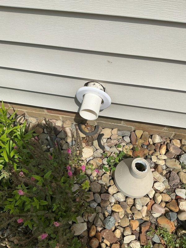 Responded to water leak complaint in basement of 46-year-old residence with basement finishing completed in 2015. Conducted thorough inspection of interior basement walls and exterior foundation perimeter to identify source of water intrusion. Exterior examination revealed compromised drainage system with detached PVC component near foundation, surrounded by river rock landscaping. Interior inspection showed moisture penetration at wall-floor junction with potential water migration through foundation. Documented conditions with photographic evidence of both exterior drainage issue and interior affected areas. Identified exterior drainage pipe discharge point as likely contributing factor to basement water infiltration.