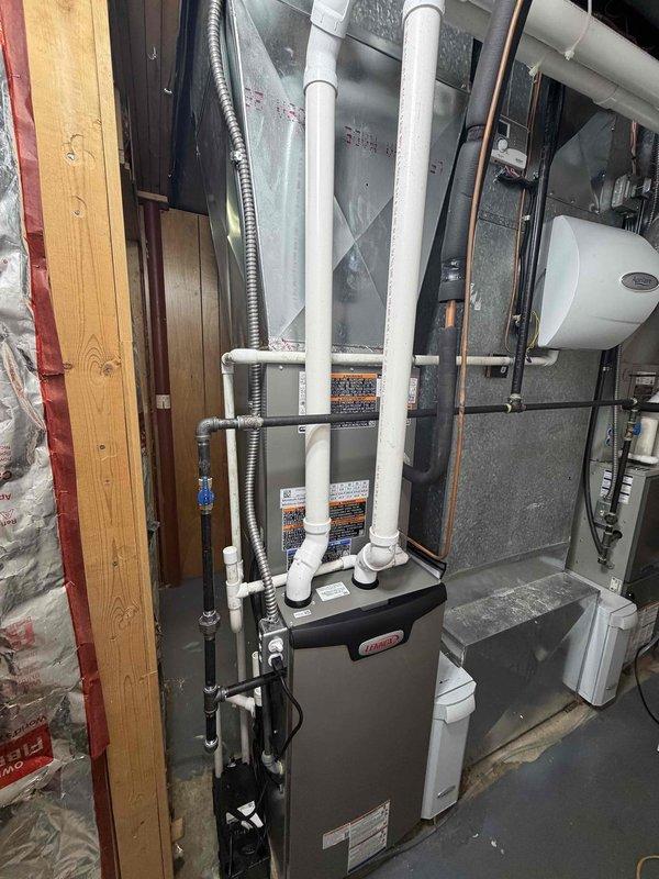 Completed 90% furnace and air conditioning system installation in basement utility room. Relocated AC unit to customer-specified location after verifying correct system in home with two HVAC systems. Installation includes new gray furnace with white PVC venting and condensate drainage, vertical air handler unit with proper electrical connections, and associated metallic ductwork. All equipment properly positioned in mechanical room alongside existing water heater, with complete duct connections, piping, and system integration. Verified proper clearances, secured all mounting hardware, and ensured all mechanical connections meet code requirements.