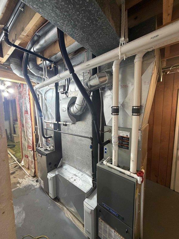 Completed 90% furnace and air conditioning system installation in basement utility room. Relocated AC unit to customer-specified location after verifying correct system in home with two HVAC systems. Installation includes new gray furnace with white PVC venting and condensate drainage, vertical air handler unit with proper electrical connections, and associated metallic ductwork. All equipment properly positioned in mechanical room alongside existing water heater, with complete duct connections, piping, and system integration. Verified proper clearances, secured all mounting hardware, and ensured all mechanical connections meet code requirements.
