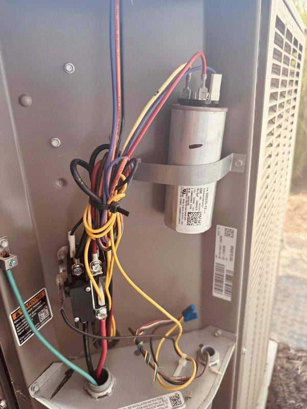 Responded to service call for 3-year-old air conditioning unit making loud thumping noise. Upon arrival, performed diagnostic inspection of indoor HVAC components including capacitor, electrical connections, and wiring harness. Utilized digital multimeter to test electrical readings and verify proper voltage levels throughout the system. All electrical connections were found secure with proper wire management via zip ties. Capacitor tested within normal operating parameters. System components including terminal blocks and conduit connections inspected and confirmed properly installed. Documented equipment condition with photographs for service records.