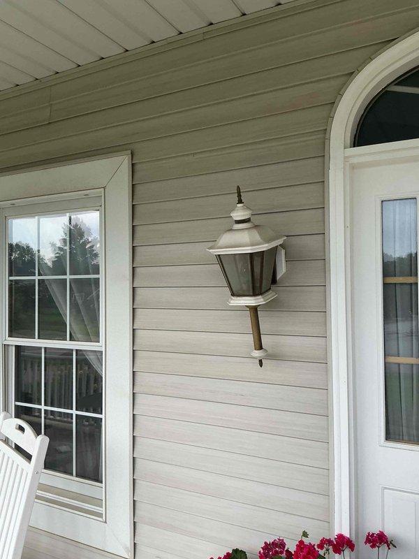 Removed existing weathered outdoor light fixture from front porch exterior wall and replaced with customer-supplied lantern-style fixture. Installed matching outdoor light fixtures on both sides of entry door adjacent to garage, ensuring proper mounting to exterior siding and secure electrical connections. All fixtures tested and verified operational upon completion.