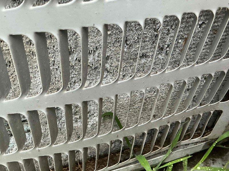 Responded to service call for air conditioning unit not cooling properly. Upon arrival, performed visual inspection of outdoor condenser unit and found significant dirt and debris accumulation on exterior louvers and ventilation grilles, restricting airflow. Noted vegetation growth around unit base and organic debris on concrete pad. Cleaned condenser coils and louvers to restore proper airflow, cleared debris from around unit perimeter, and verified system operation. Unit now cooling effectively with improved air circulation.
