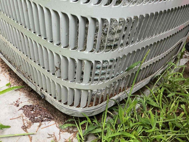 Responded to service call for air conditioning unit not cooling properly. Upon arrival, performed visual inspection of outdoor condenser unit and found significant dirt and debris accumulation on exterior louvers and ventilation grilles, restricting airflow. Noted vegetation growth around unit base and organic debris on concrete pad. Cleaned condenser coils and louvers to restore proper airflow, cleared debris from around unit perimeter, and verified system operation. Unit now cooling effectively with improved air circulation.